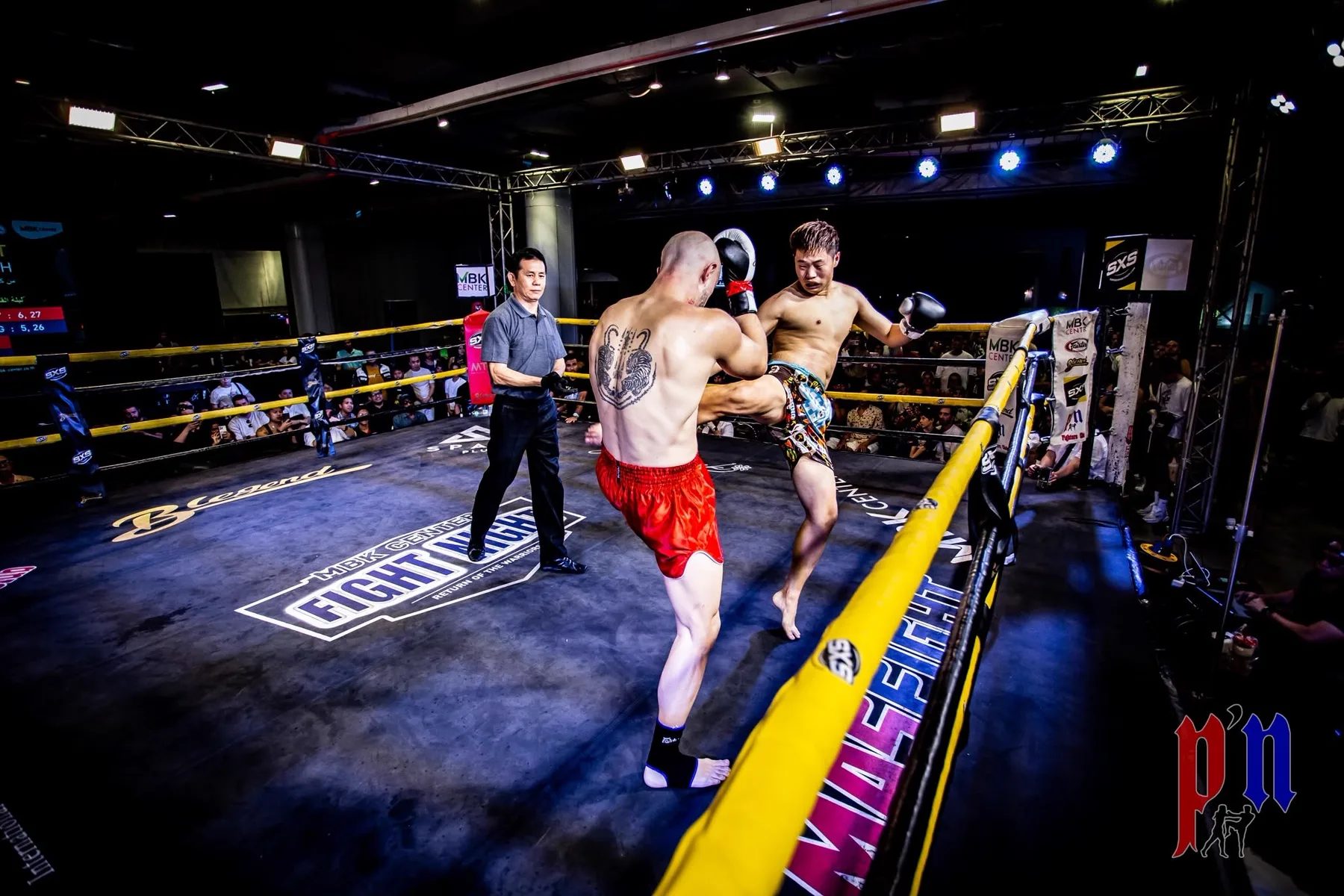 Two fighters trade kicks in the MBK Fight Night ring while the crowd watches from around the ropes