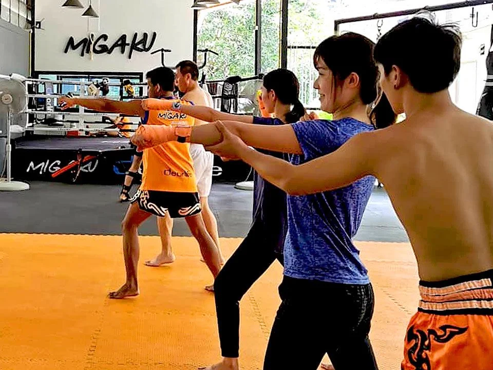 A group training session at Migaku, with students throwing punches together on the gym floor